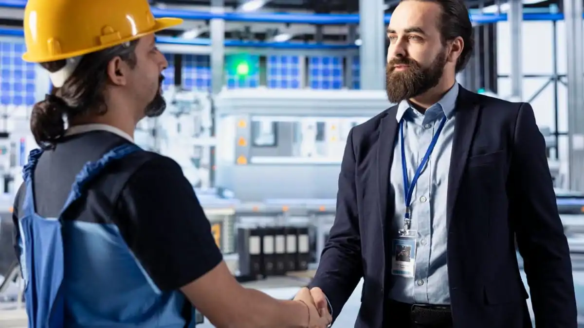 Manager félicitant un technicien dans un atelier industriel