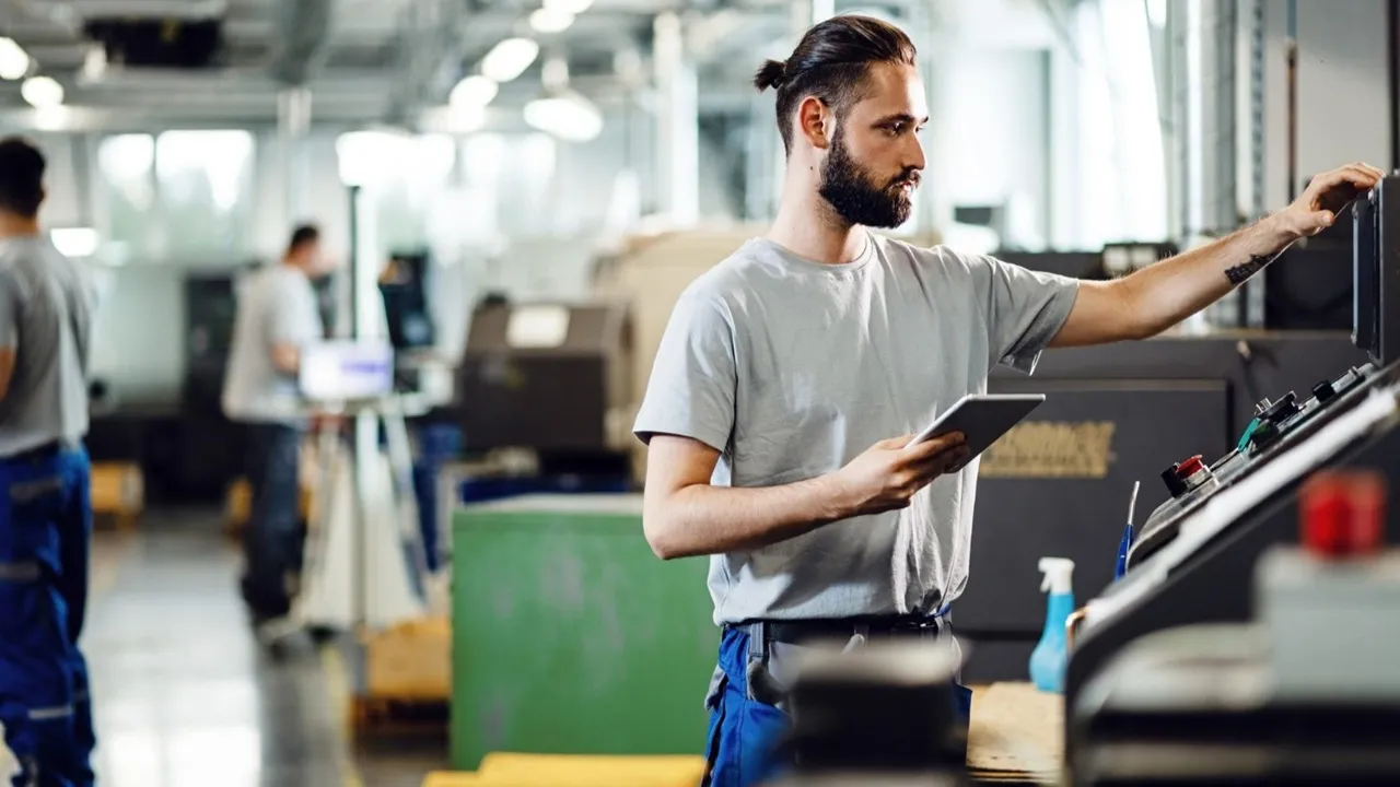 Ingénieur utilisant une tablette pour contrôler une machine et analyser le fonctionnement d’un équipement industriel